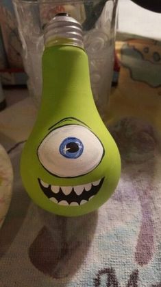 a green light bulb with an evil face painted on it's side sitting on a table