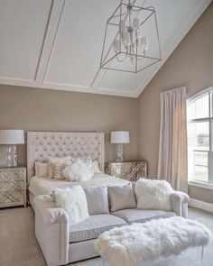 a large white couch sitting under a chandelier next to a bed in a bedroom