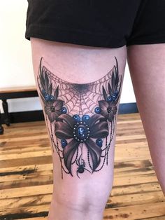 a woman's leg with a spider web and flowers tattoo on the side of her thigh