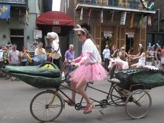 a woman riding on the back of a bike next to a man in a costume