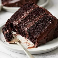 a slice of chocolate cake on a white plate with a fork next to the piece