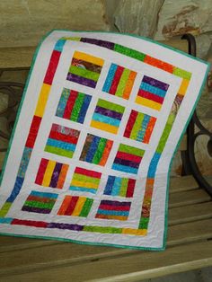 a multicolored quilt sitting on top of a wooden bench