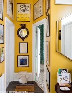 a hallway with yellow walls and pictures hanging on the wall, along with a mirror