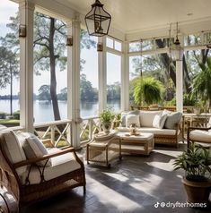 a porch with wicker furniture and large windows overlooking the water in front of it