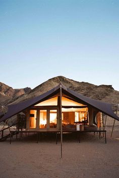 a tent set up in the desert with mountains in the background