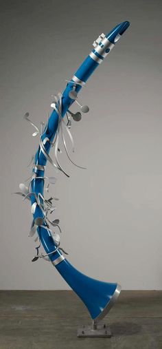 a blue and silver musical instrument sculpture on a metal stand with confetti sprinkles