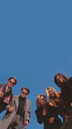 a group of people standing next to each other on top of a hill with a blue sky in the background