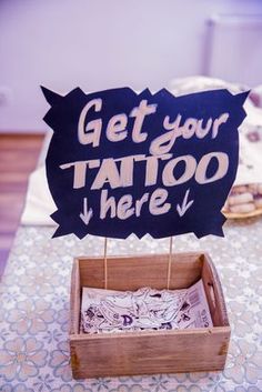 a sign that says get your tattoo here on top of a table with cookies in the background