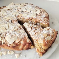 a white plate topped with a cake covered in powdered sugar and sliced into slices