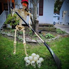 a skeleton is holding a broom and some balls in the grass with it's head turned upside down