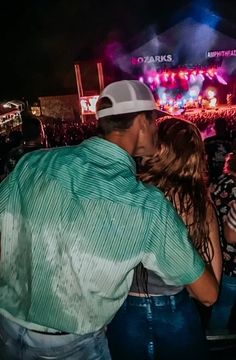 a man and woman kissing in front of an audience at a music festival on stage