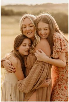 three girls hugging each other in a field