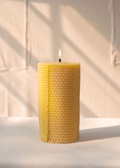 a yellow candle sitting on top of a white table