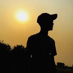 the silhouette of a man wearing a hat is shown in front of the setting sun