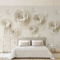 a white bedroom with large paper flowers on the wall