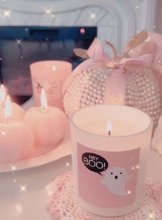 a pink candle sitting on top of a table next to other candles and decor items