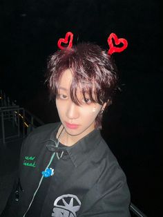 a young man with red horns on his head wearing a black shirt and heart shaped hair clips