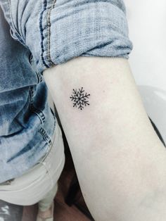 a small snowflake tattoo on the arm