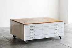 a white and wooden table on wheels in an empty room