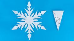 an origami snowflake is cut out of paper and placed on a blue background