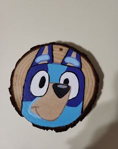 a blue and brown bear face painted on a piece of wood