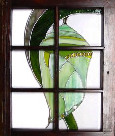 a stained glass window with a green plant in it's center and leaves on the outside