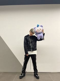 a man holding up a stuffed animal in front of a wall