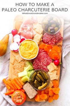 a platter filled with meats, vegetables and crackers on top of a white towel