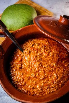 a bowl filled with chili next to a lime