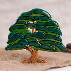 a wooden sculpture of a tree with green leaves on it and a book next to it