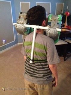 a young boy is carrying silver wrapped presents on a stick in his living room,