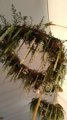 an arrangement of flowers and greenery hanging from the ceiling