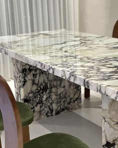 a marble dining table with green chairs around it