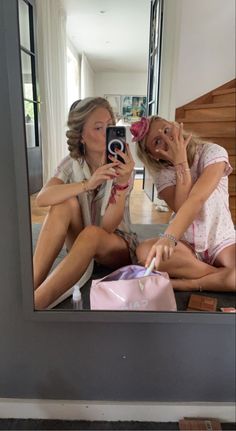 two women sitting on the floor in front of a mirror