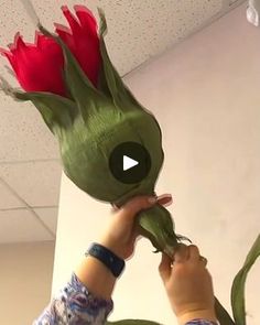 a person holding up a fake flower to the ceiling