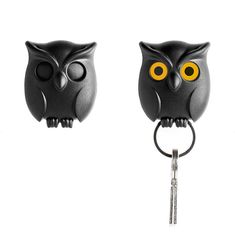 two black owls with yellow eyes are attached to a keychain on a white background