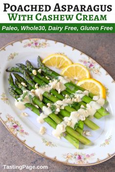 grilled asparagus with cashew cream on a white plate topped with lemon wedges