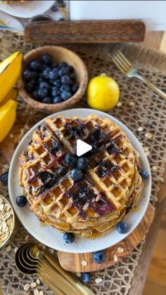 a stack of waffles on a plate with blueberries and bananas next to it