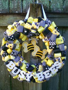 a yellow and black baby wreath hanging on a wooden fence with the word bee in it