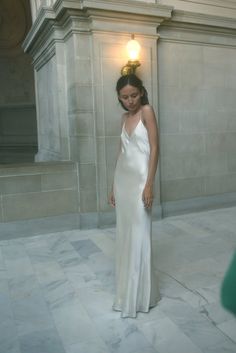 a woman in a white dress standing next to a building