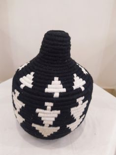 a black and white knitted vase sitting on top of a table next to a wall