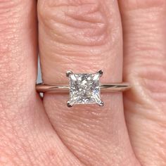 a woman's hand with a diamond ring on her left hand and the other hand holding an engagement ring