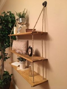 three wooden shelves with plants and other items on them hanging from the wall next to a potted plant