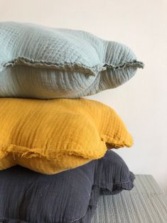 three pillows stacked on top of each other in different colors and sizes, one yellow the other blue