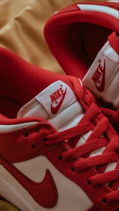 a pair of red and white sneakers on top of a brown bedding sheet,