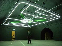 a man is standing in an empty room with neon lights on the ceiling and floor