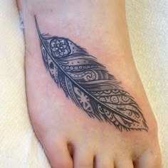 a black and white feather tattoo design on the right side of the foot with an intricate pattern