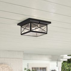 a light hanging from the side of a white house next to a porch with potted plants