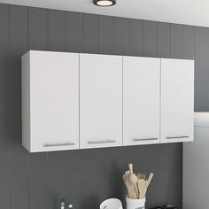 a kitchen with gray walls and white cupboards on the wall, along with utensils