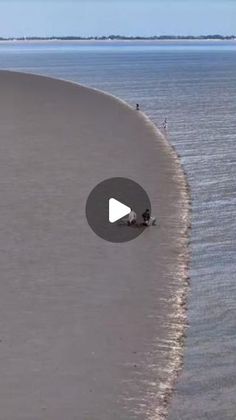 an aerial view of the beach with people walking on it and one person standing in the water